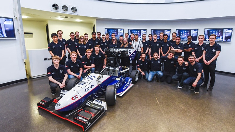 A group of students stood around a racing car